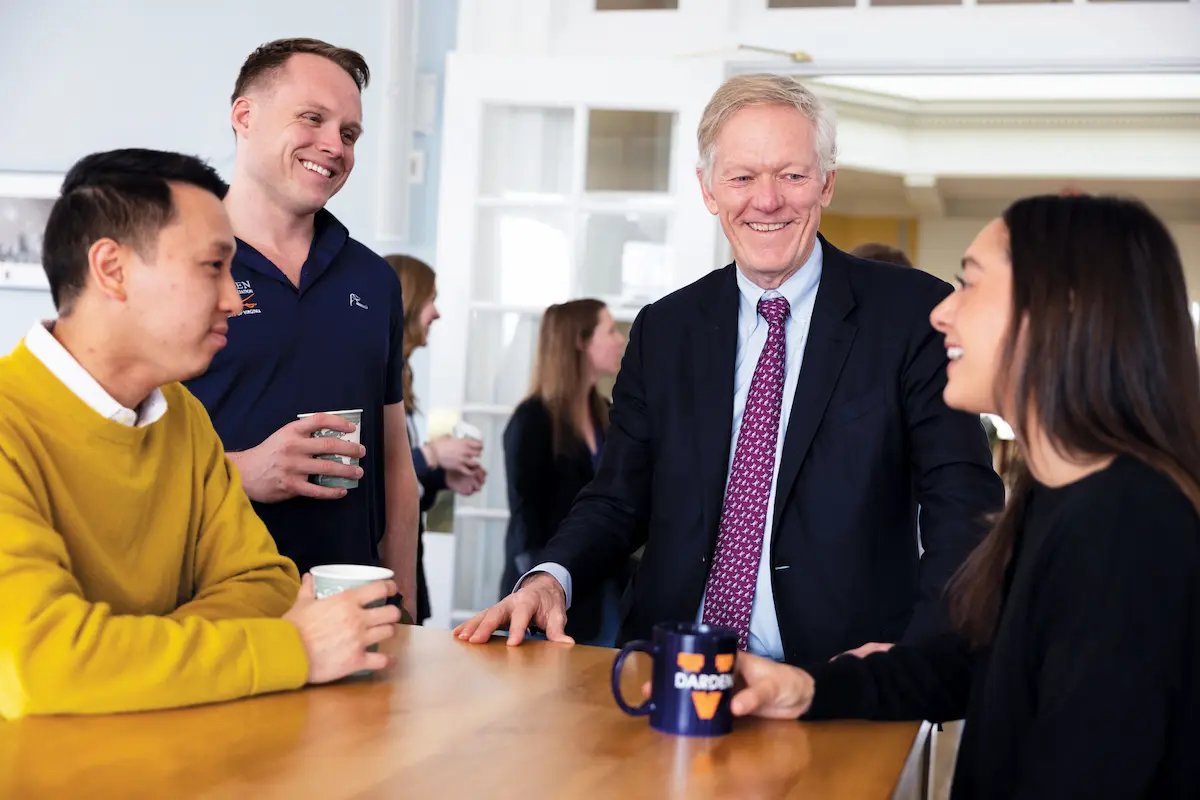 The dean of Darden smiling and talking with three people around a table