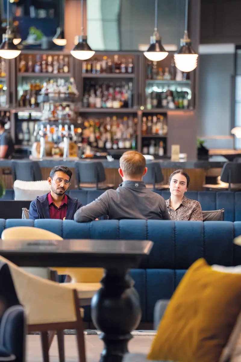 Three people seated in The Forum Hotel lobby/restaurant